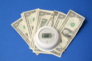 Money underneath a thermostat representing how to save money on Air Conditioning