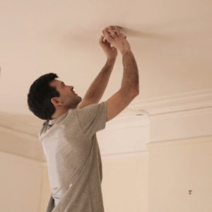Man changing the batteries on his smoke detector